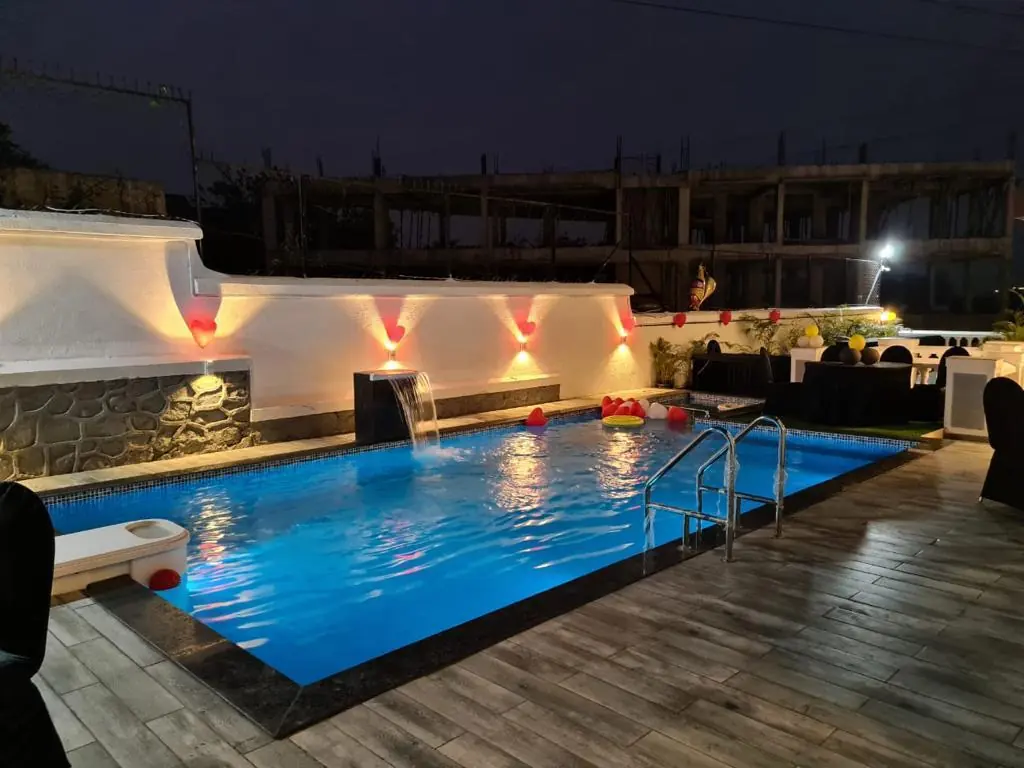 Private pool lit at night, with the waterfall feature — Carpe Diem, Lonavala