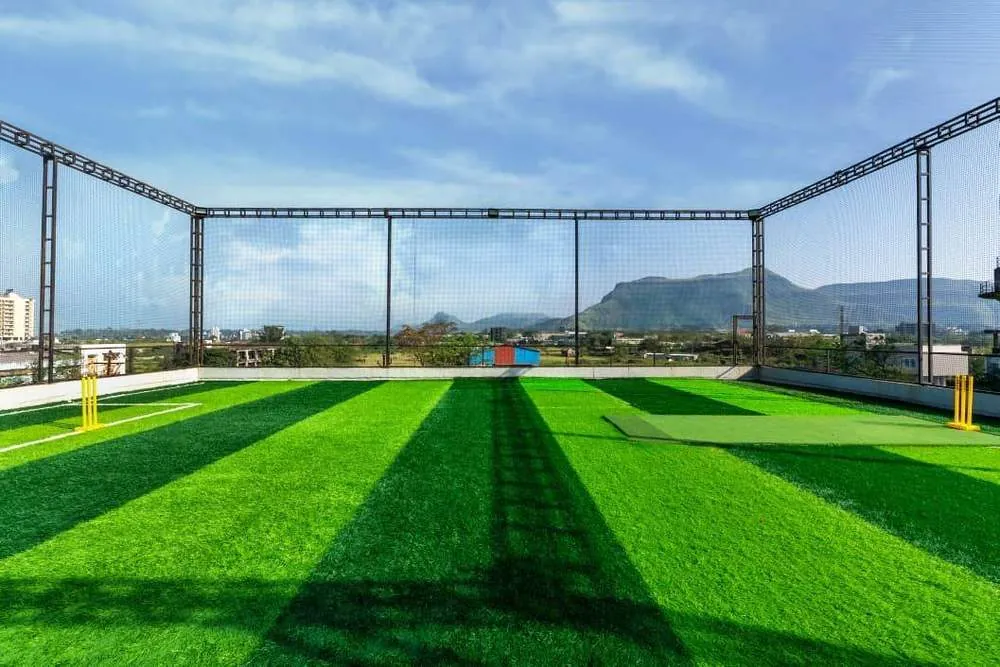The rooftop cricket turf at Greenwood Villa, Igatpuri, seen end-on with nets and stumps