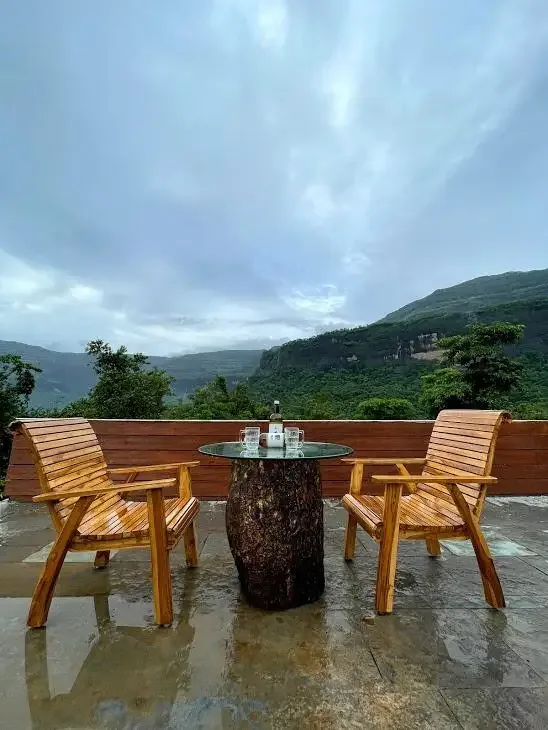 Two chairs and a table on the deck at dusk — Misty Cascades, Karjat