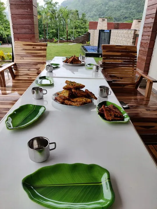 The long outdoor dining table beside the lawn — Misty Cascades, Karjat